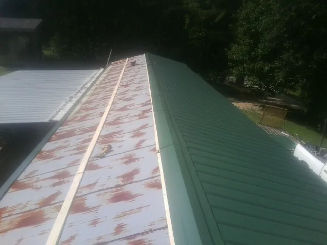 Old rusted panels beside newly installed green metal roofing — Wind Damage Roof Repair by Roofing Brothers in Bayport