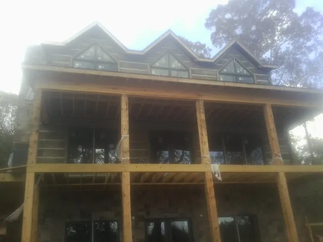 Dormers and porch framing on a large log home under construction — Roof Coating work by our crew in Bayport