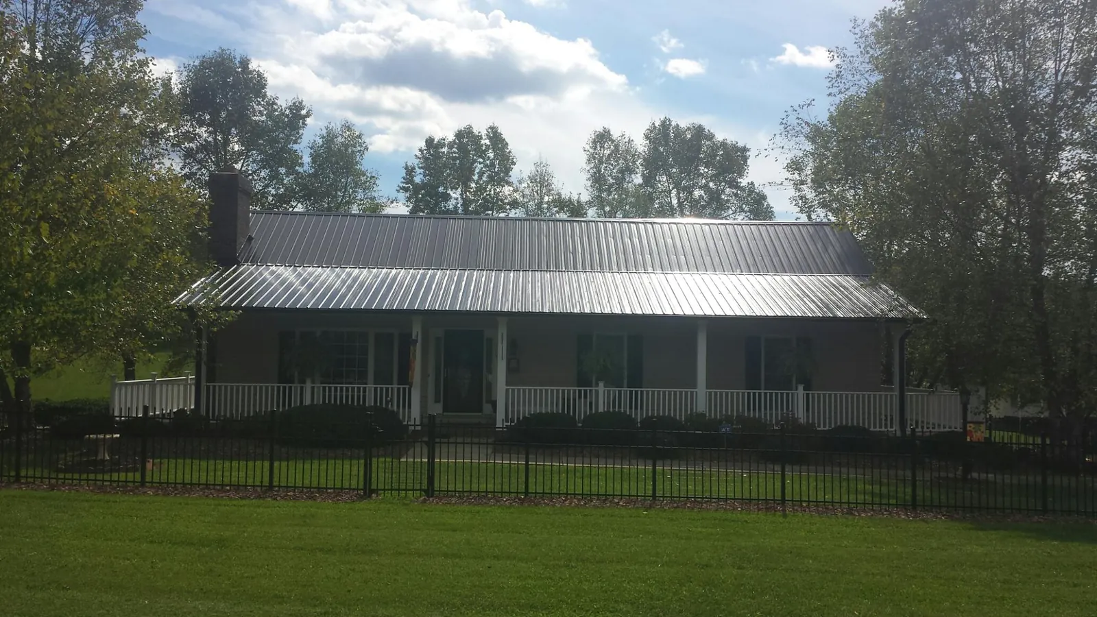Gray metal roof on a brick ranch with a full width front porch — Gutter Guard Installation work by our crew in Bayport