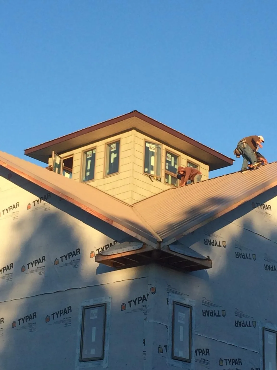 Roofers working around a rooftop cupola on a new metal roof at sunset — Roof Waterproofing in Bayport by Roofing Brothers
